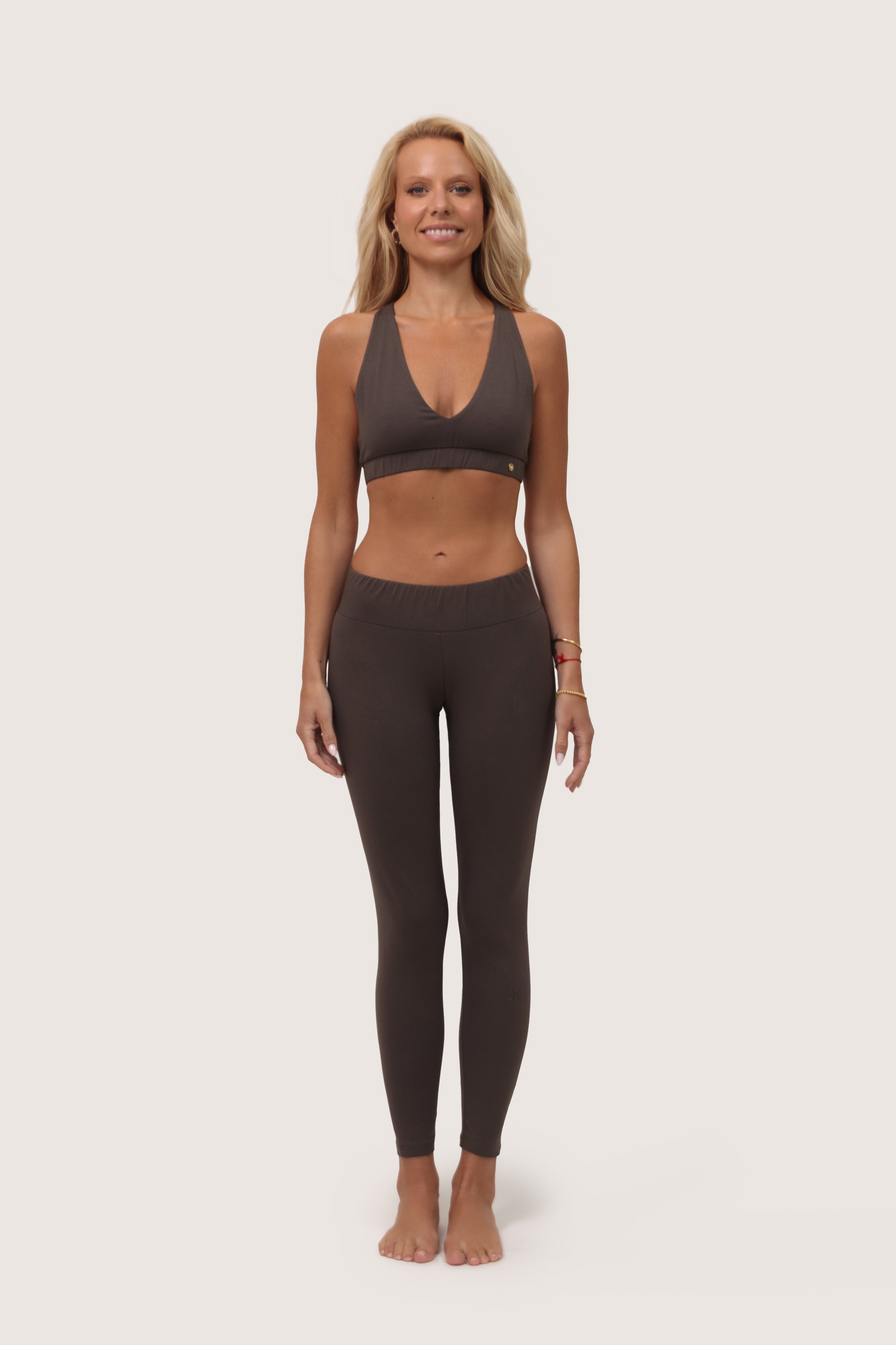 Woman wearing a brown sports bra and leggings set on a white background